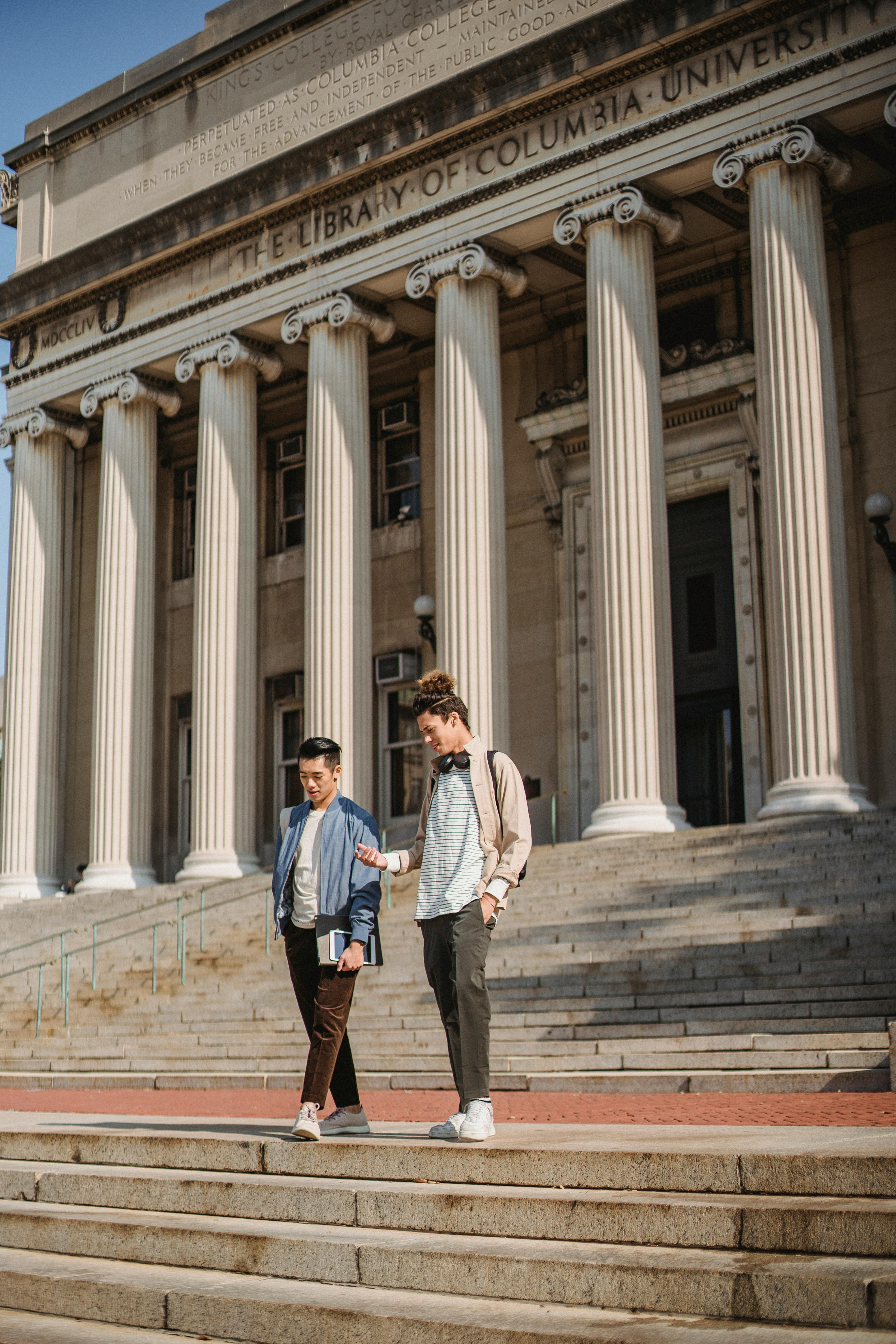 Two young men descend steps at Columbia University, showcasing campus life and education themes.